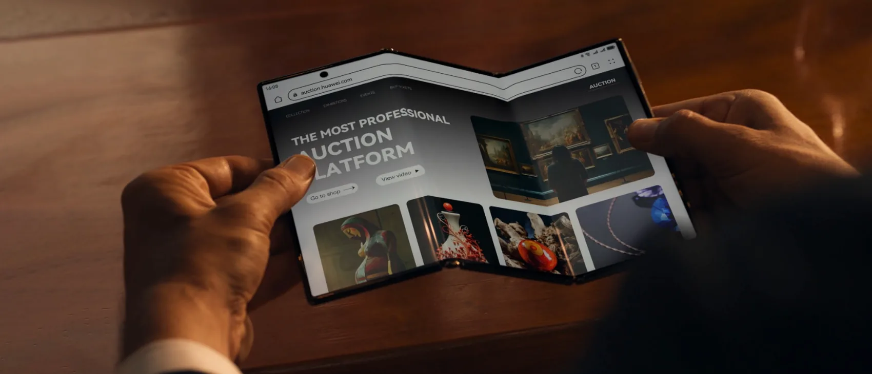 Original foldable phone image held in hands on a warm table.
